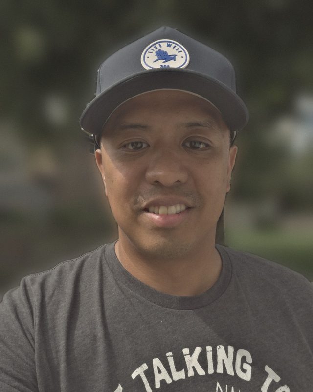 JG, founder of Ozanam Tech, smiling in a navy cap